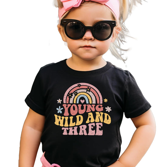 Close-up of Young Wild Three rainbow text design on birthday shirt