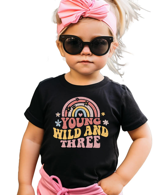 Close-up of Young Wild Three rainbow text design on birthday shirt