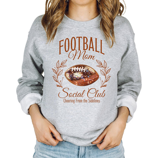 Model wearing Football Mom Social Club pullover sweatshirt in gray with glitter football print