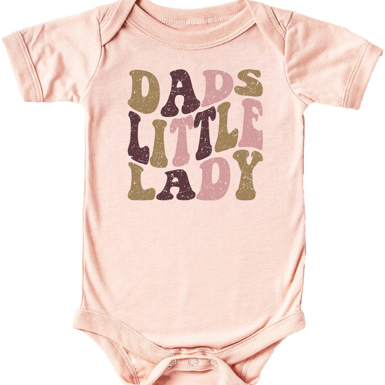 Close-up of distressed retro font Dad's Little Lady design on peach baby bodysuit