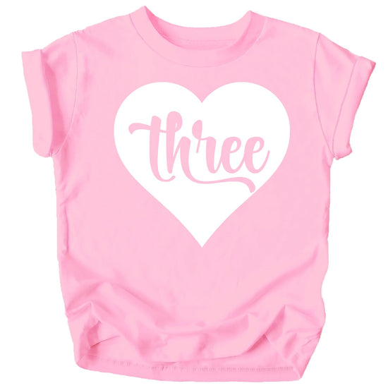 Flat lay of pink girls third birthday shirt with heart and number three design