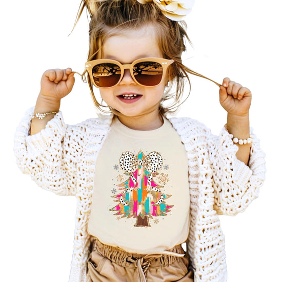 Flat lay of pink women's Christmas tee featuring Dalmatian bow-topped glitter tree graphic