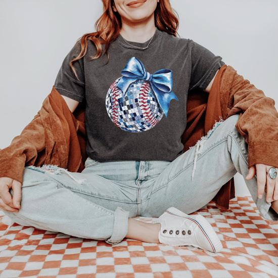 Model wearing oversized disco softball graphic tee with blue bow, styled casually