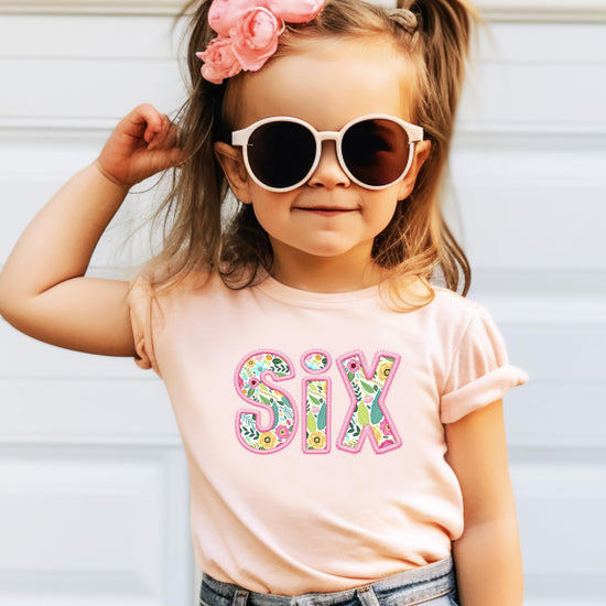 Flat lay of peach youth birthday tee featuring SIX floral design for girl turning 6
