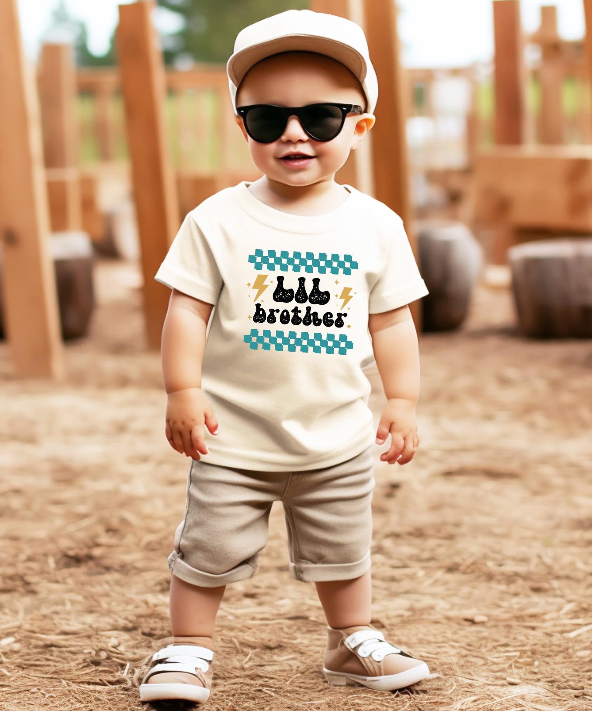 Toddler boy wearing little brother retro lightning graphic shirt in natural color