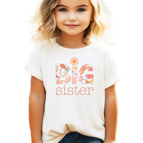 Girls wearing a peach floral daisy Big Sister graphic t-shirt, youth sizing