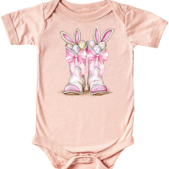 Front view of white baby one-piece with western Easter bunny boots graphic in pink and peach