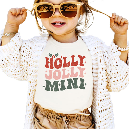 Close-up of Holly Jolly Mistletoe graphic print on natural matching Christmas tee