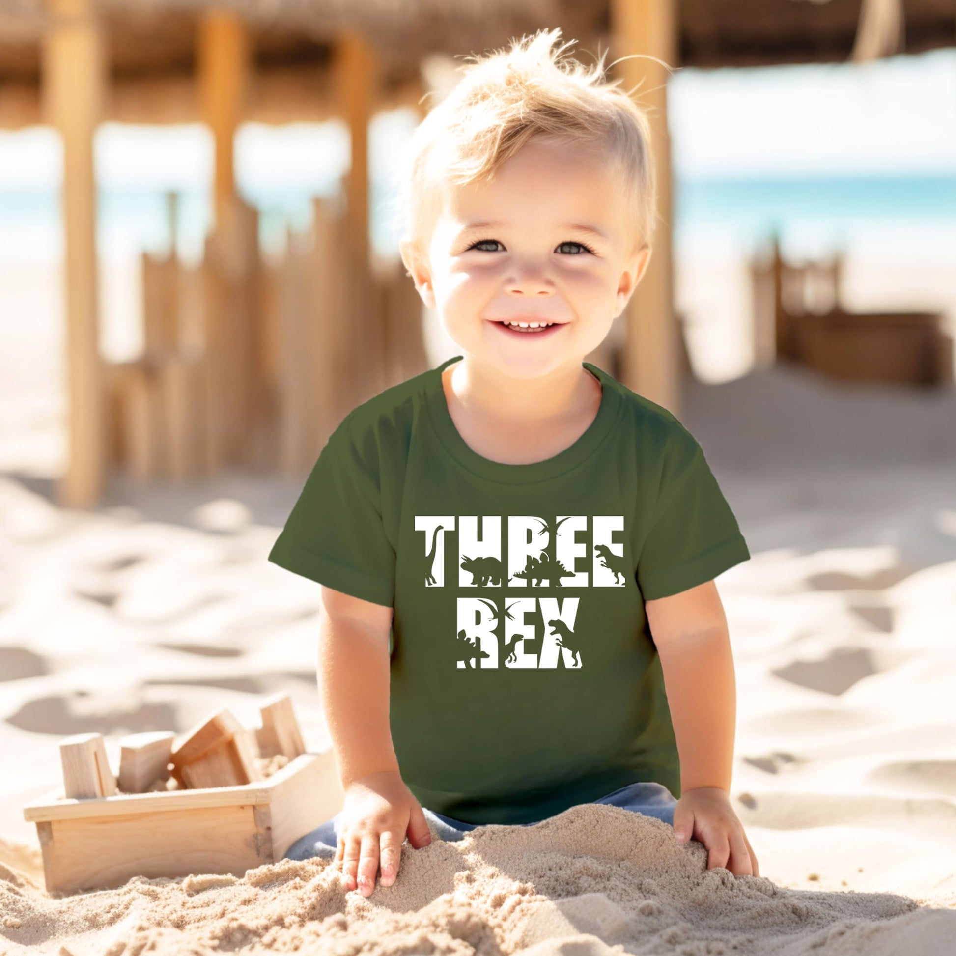 Toddler wearing Three Rex 3rd birthday dinosaur tee in military green