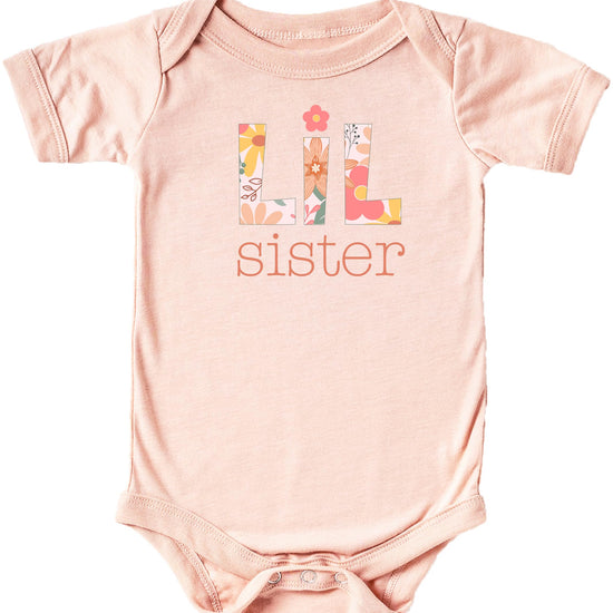 Baby girl wearing peach Lil Sister floral bodysuit, sibling matching outfit