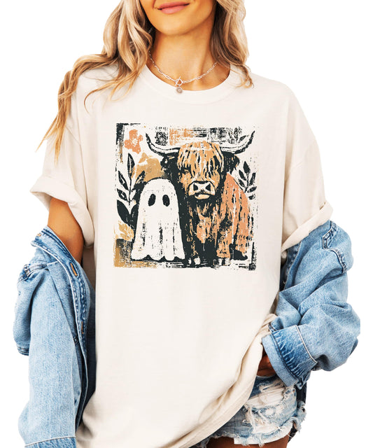 Close-up of ghost and highland cow Halloween graphic print on women's ivory tee shirt