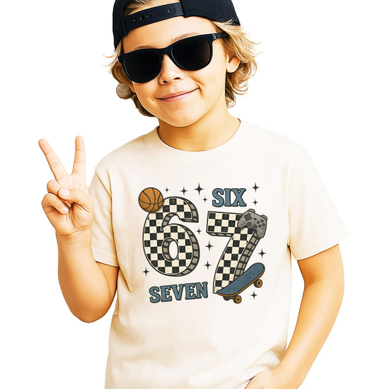 Boys natural graphic tee with checkered 6 7 meme design featuring a basketball, skateboard, and game controller