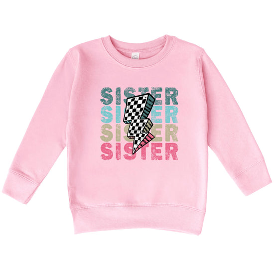 Flat lay of colorful SISTER toddler sweatshirt showing full print design and pink fabric