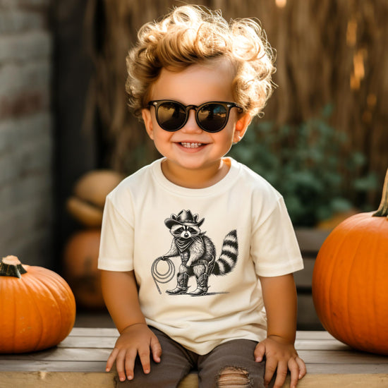 Front view of raccoon cowboy graphic kids t-shirt in natural color with vintage western style print