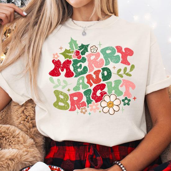 Flat lay of ivory Merry and Bright distressed Christmas shirt showing full graphic design