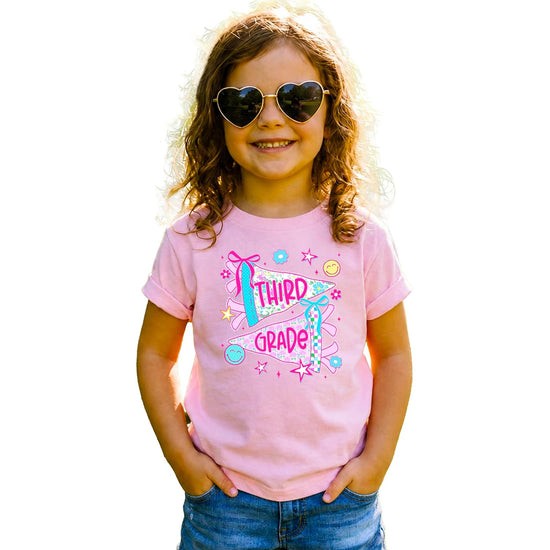Girl wearing third grade floral pennant tee styled with jeans, perfect for first day of school outfit