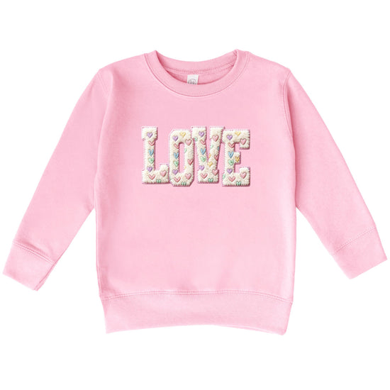 Close-up of ink-printed retro LOVE design with pastel hearts on pink sweatshirt