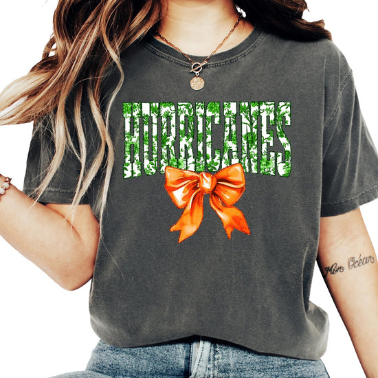 Side or lifestyle view of women's ivory Hurricanes floral graphic tee with orange bow detail