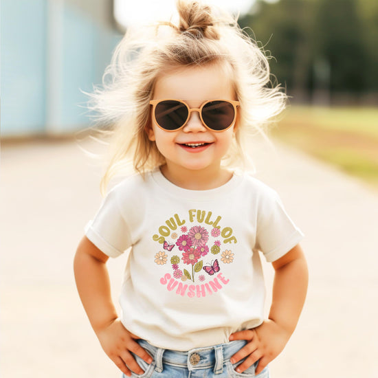 Girls floral t-shirt flat lay showing full design with retro sunshine and flower motifs