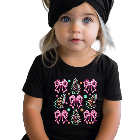 Close-up of vibrant neon holiday graphic with Christmas trees and bows on black women's tee