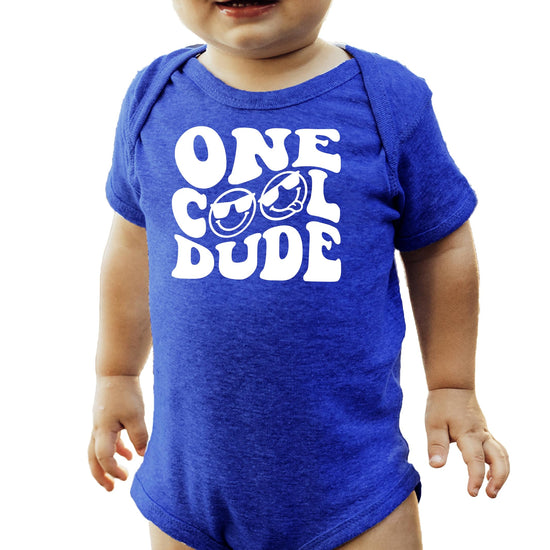 Baby boy wearing One Cool Dude black first birthday bodysuit with retro sunglasses graphic
