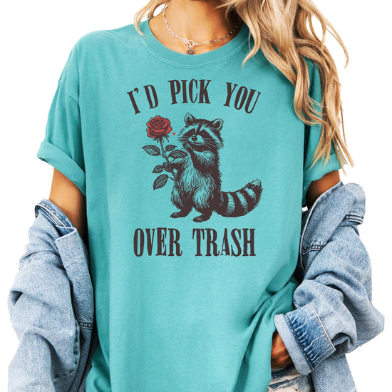 Women's ivory graphic tee with a raccoon holding a rose and text 'I'd Pick You Over Trash' — funny Valentine's Day shirt
