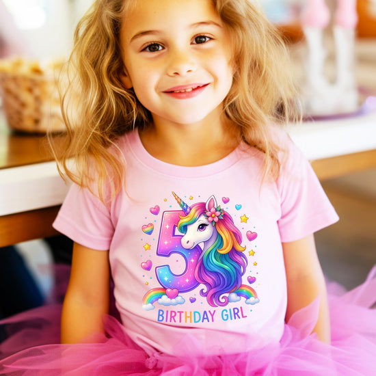 Young girl wearing pink 5th birthday unicorn graphic tee at party celebration