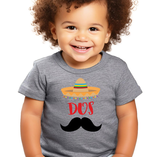 Toddler boy wearing a fiesta-themed Dos 2nd birthday shirt with mustache graphic