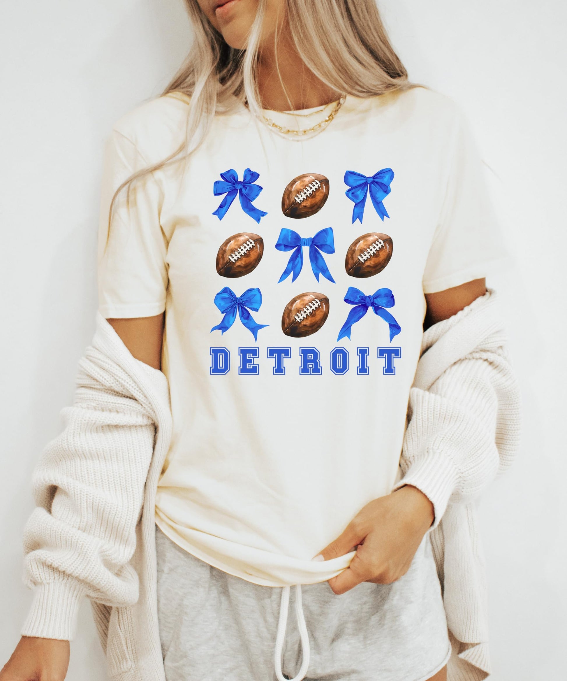 Detail shot of vibrant blue coquette bows and football graphic on women's Detroit shirt