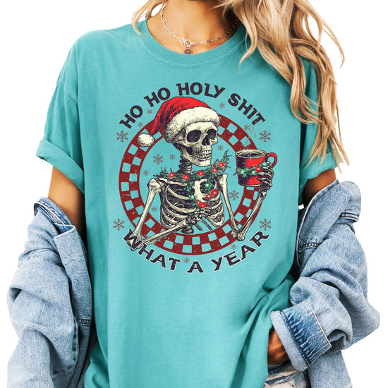 Close-up of humorous holiday skeleton holding warm drink print on seafoam Christmas shirt
