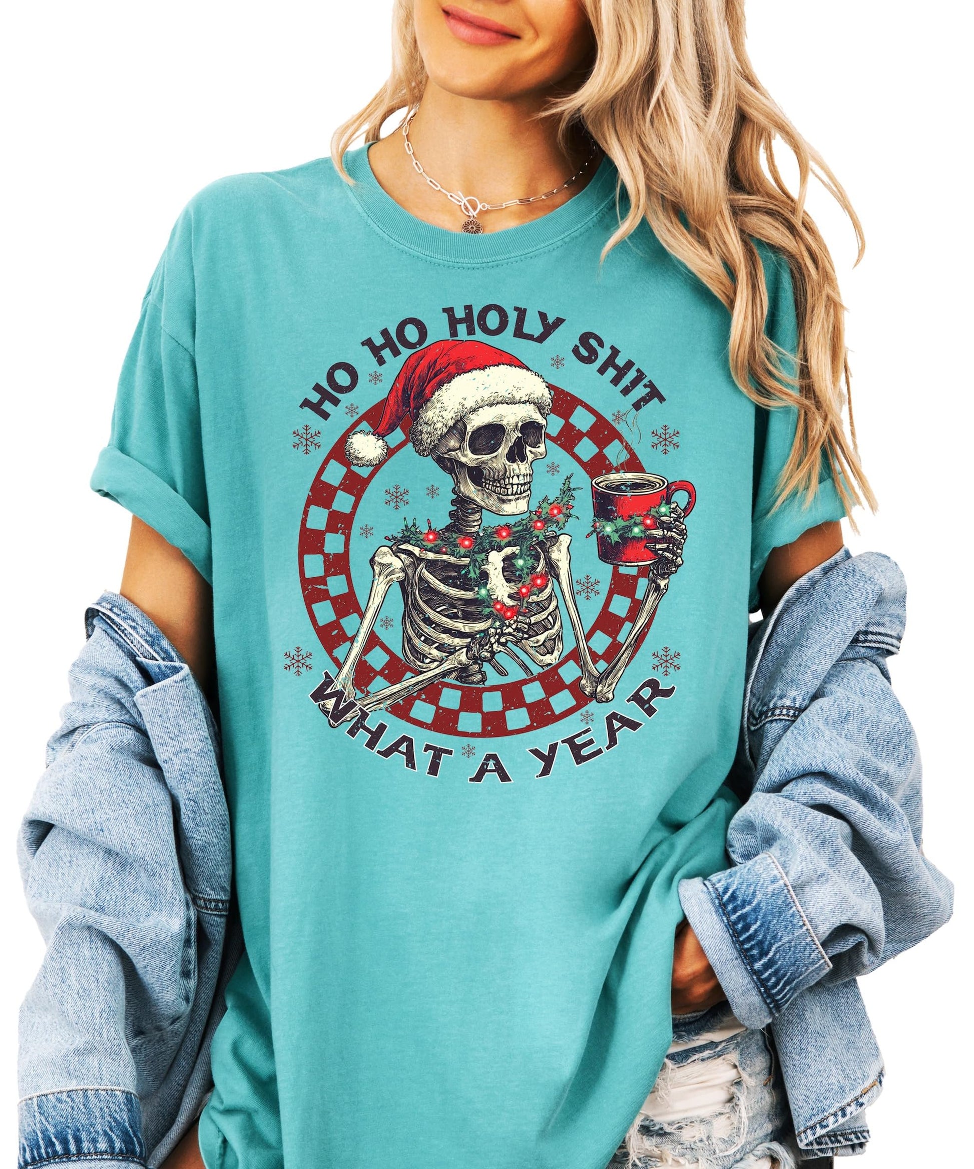 Close-up of humorous holiday skeleton holding warm drink print on seafoam Christmas shirt