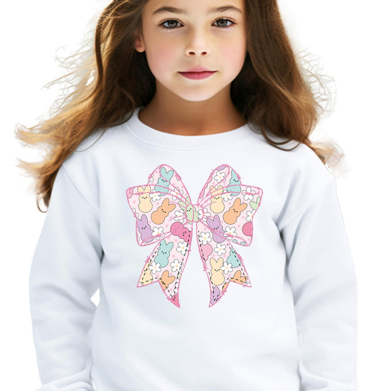 Young girl wearing a pastel pink Easter sweatshirt with bunnies and floral accents