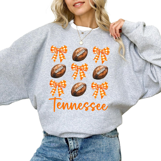 Flat lay of gray Tennessee football sweatshirt displaying orange bows and football theme