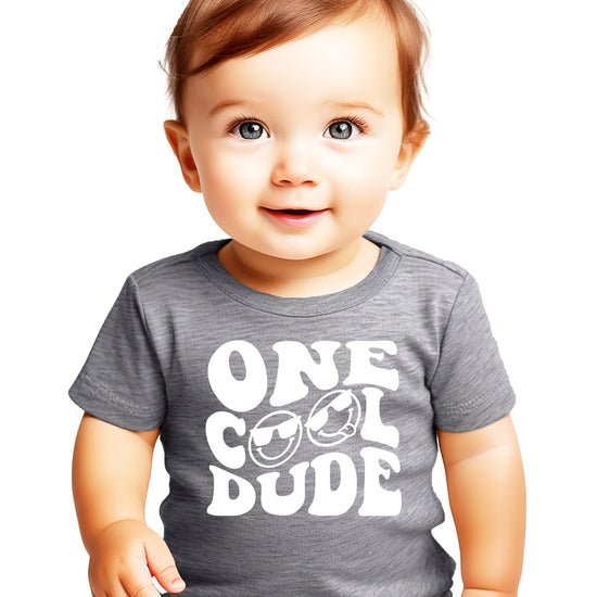 One Cool Dude first birthday outfit flat lay showing shirt and bodysuit options for boys