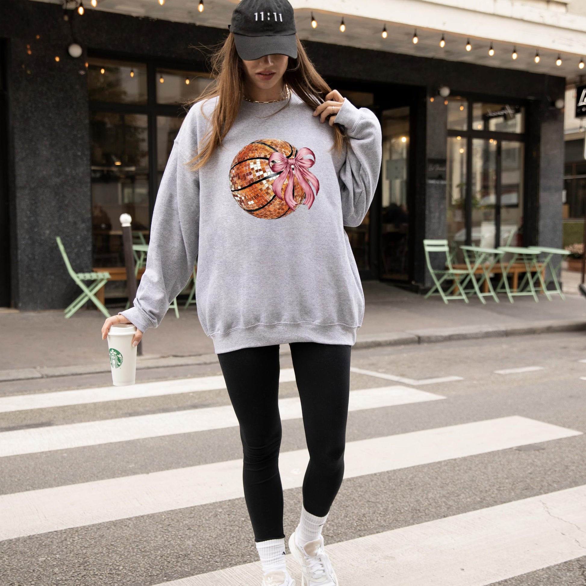 Flat lay of gray graphic pullover sweatshirt featuring a disco basketball topped with a pink coquette bow