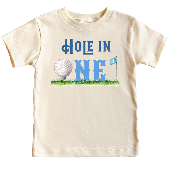 Flat lay of boys first birthday golf shirt showing full Hole in One graphic design on natural tee