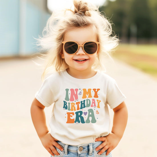 Young girl wearing peach 'In My Birthday Era' birthday graphic t-shirt for kids