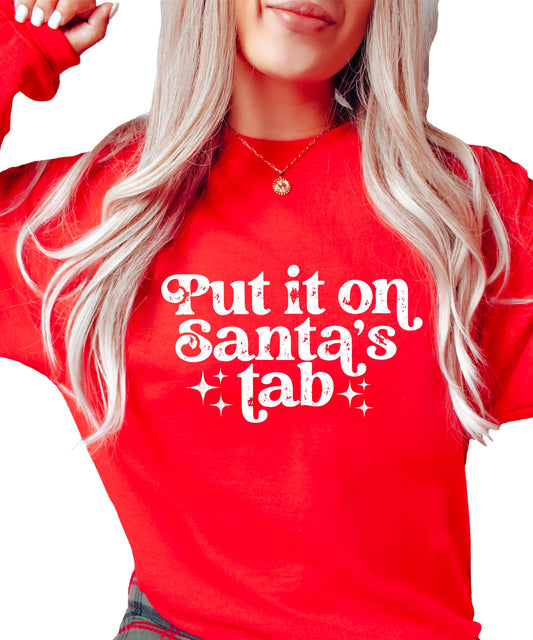 Woman wearing a red 'Put It on Santa's Tab' funny Christmas pullover sweatshirt with bold holiday graphic print