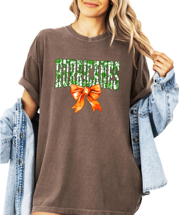 Women's ivory graphic tee with 'Hurricanes' in green floral letters and orange bow accent for school spirit