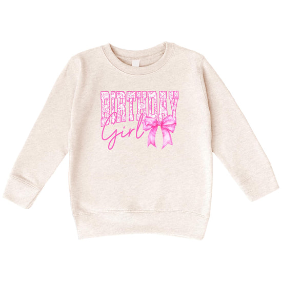 Close-up of Birthday Girl bow sweatshirt showing sparkly pink lettering and bow graphic detail