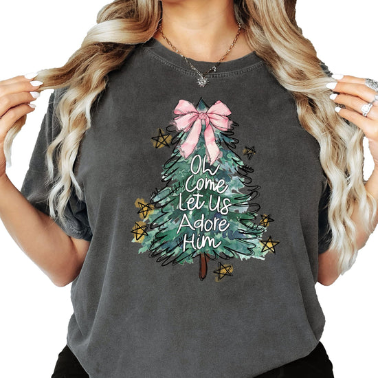 Seafoam women's tee with illustrated Christmas tree, pink bow topper, and Oh Come Let Us Adore Him graphic