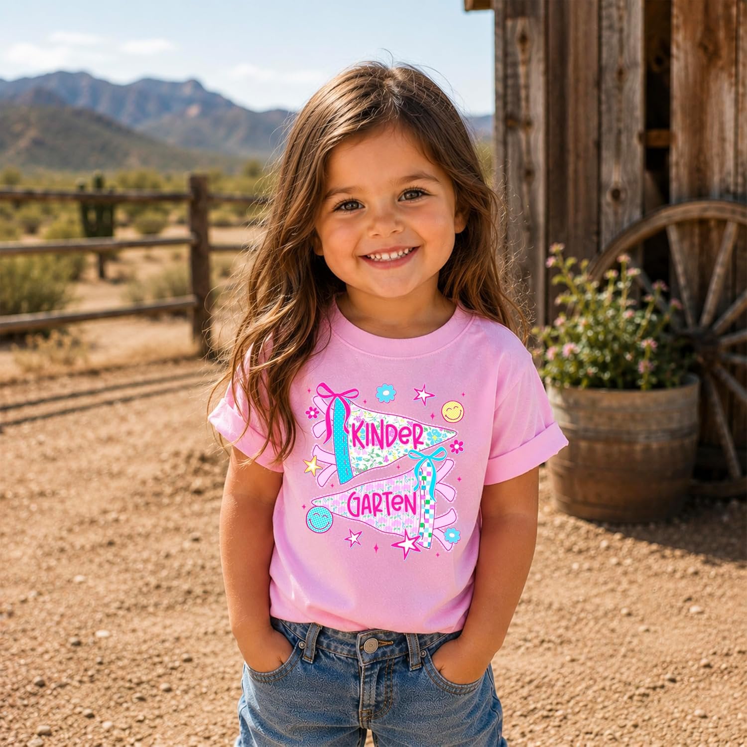 Young girl wearing pink kindergarten floral pennant graphic tee styled as a first-day-of-school outfit