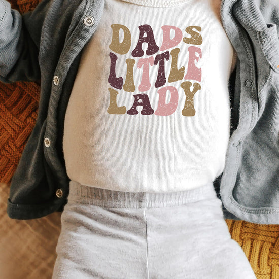 Baby girl wearing Dad's Little Lady snap bodysuit with retro graphic print