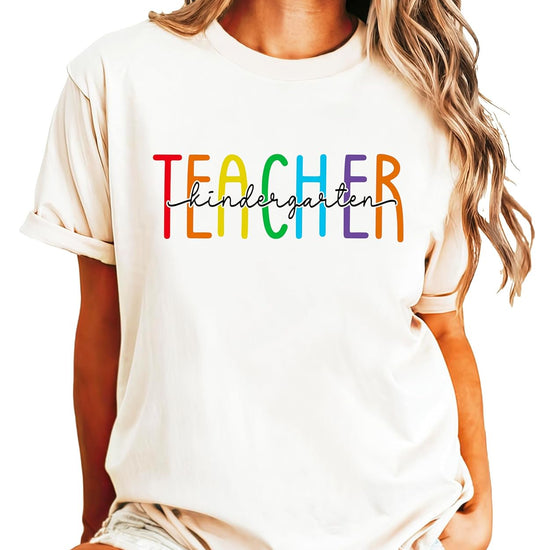 Close-up of rainbow TEACHER design with kindergarten script lettering on pink cotton tee