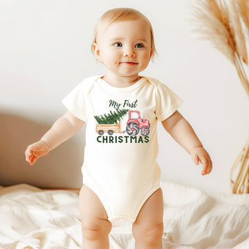 Close-up of tractor pulling Christmas tree design on infant bodysuit, first Christmas outfit for baby boy