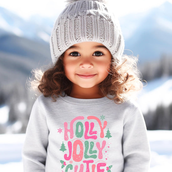 Detail shot of Holly Jolly Cutie Christmas sweatshirt print showing pink and green bubble lettering