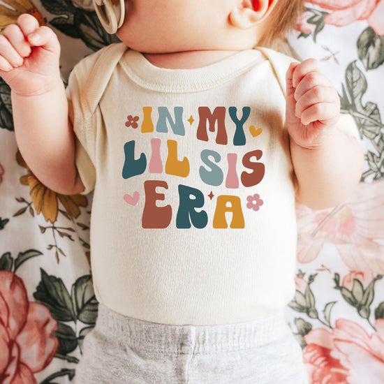 Olive Loves Apple Little Sister Era bodysuit shown on infant, lifestyle photo