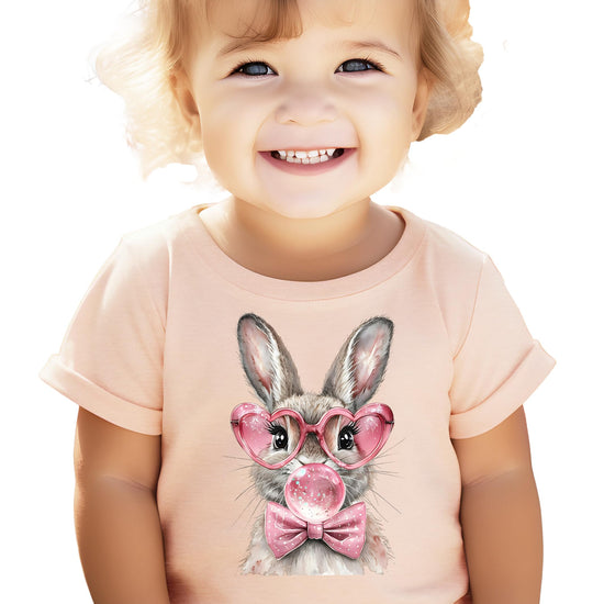 Toddler Easter graphic tee featuring cute bunny in heart-shaped glasses on peach fabric