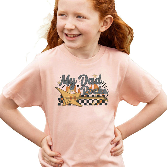 Close-up of My Dad Rocks electric guitar and flame graphic print on kids' peach t-shirt