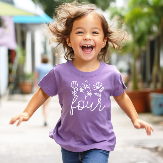 Flat lay of girls fourth birthday floral graphic tee in purple